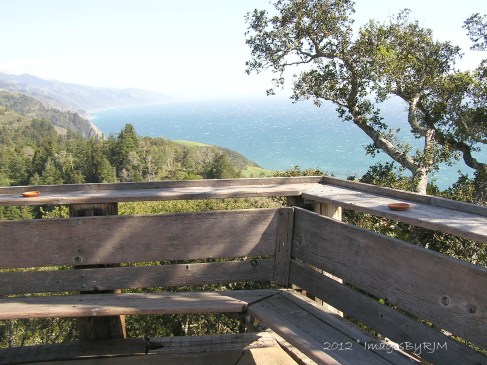 Wooden corner bench and railing overlooking Pacific Ocean from Nepenthe's Restaurant in Big Sur, California.