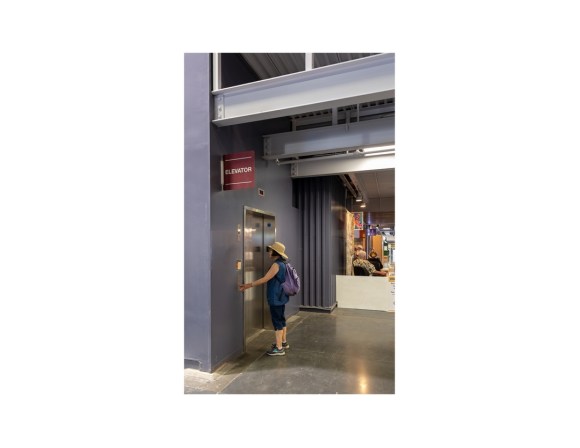 Woman standing at elevator door inside building at California State Fair.