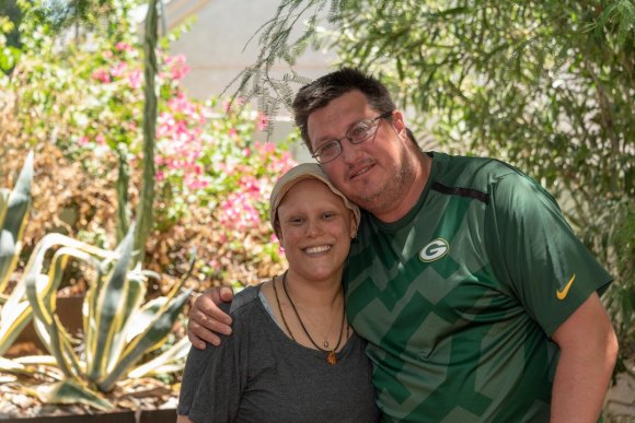 Woman and man facing forward, smiling and embracing.