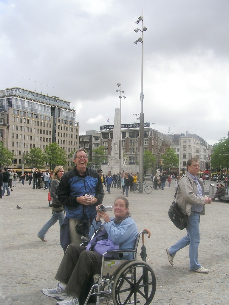 Laughing man. with young woman in wheelchair at Dam Square, Amsterdam.
