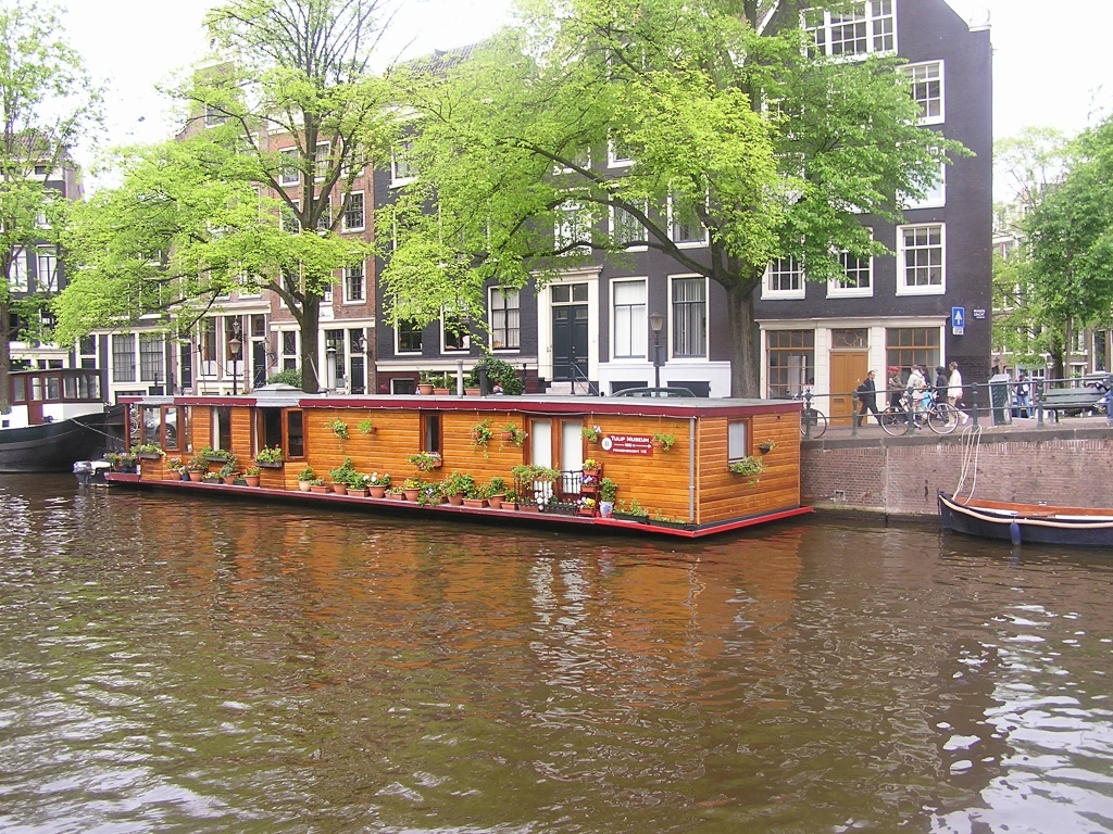 Wooden houseboat docked on side of canal in Amsterdam.